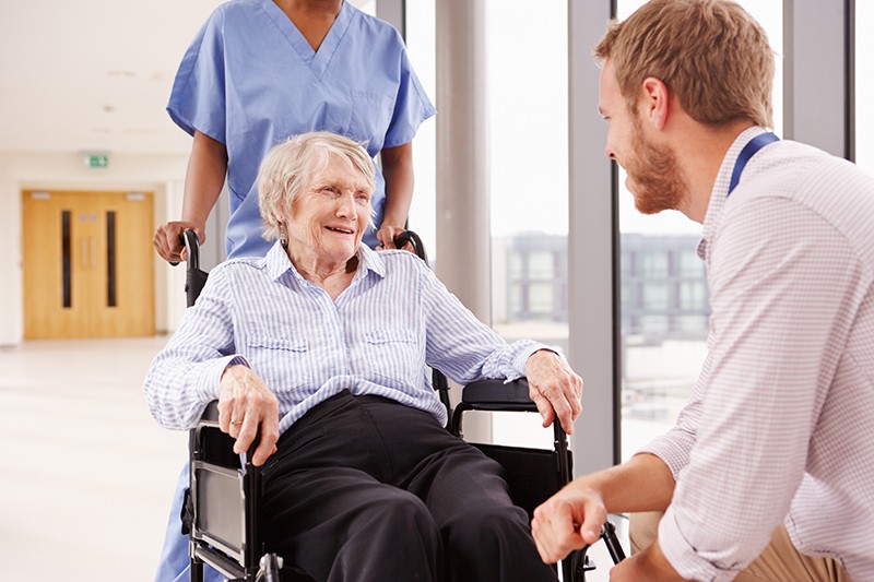 Doctor talks with older patient in exam room, long-term care in Lewisville, TX
